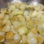 Cipolle in padella per preparazione ricetta polenta con funghi e cipolle, senza grassi animali piatto vegano vegetariano